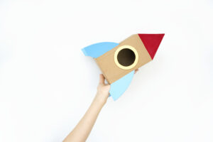Hand holding spaceship rocket on white background